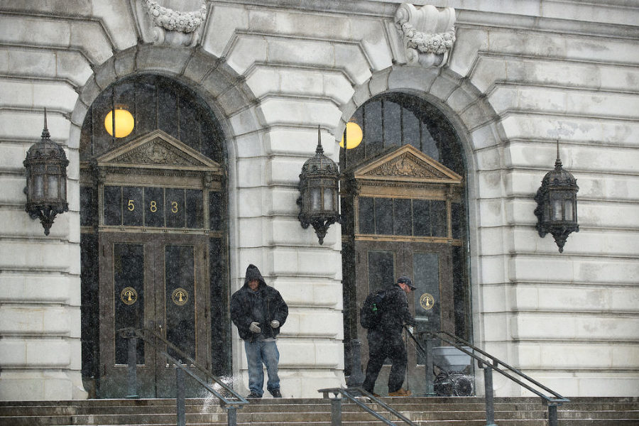 Two men spread salt on the steps of the Brennan Courthouse on Newark Avenue in Jersey City during a snowstorm on Monday, Jan. 26, 2015. Reena Rose Sibayan | The Jersey Journal