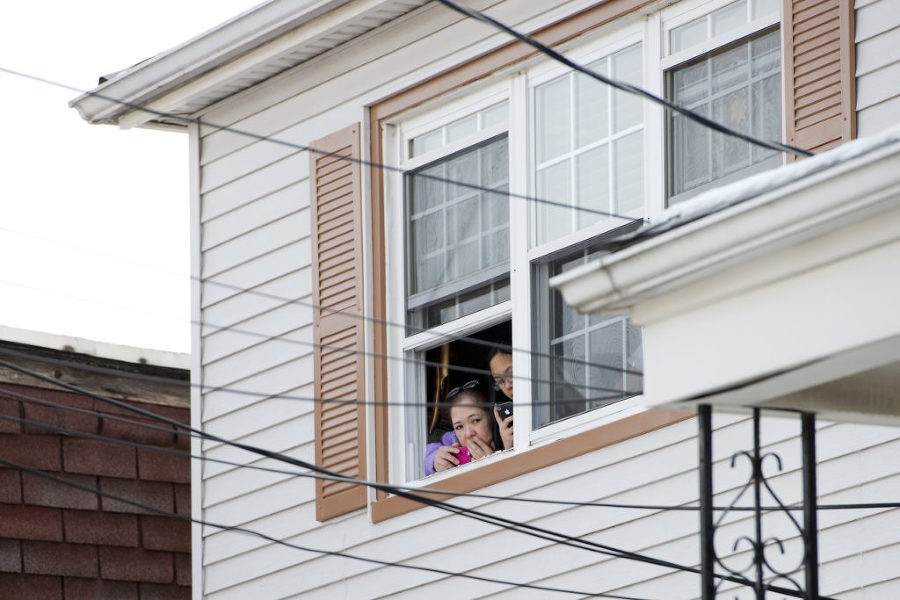 Neighbors watch as the bodies of two people found dead at 14 West 10th Street in Bayonne are removed from the home on Tuesday, Jan. 27, 2015. Reena Rose Sibayan | The Jersey Journal