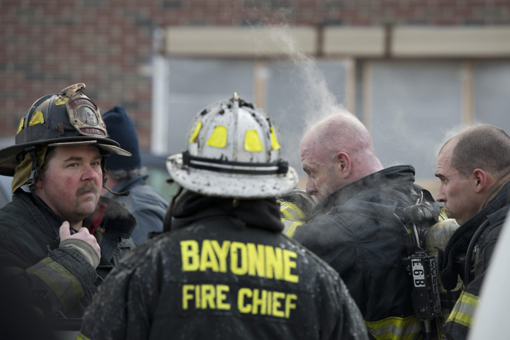 Steam rises out of firefighters responding to a five-alarm blaze that ripped through two attached homes in Bayonne at 12 and 14 West 34th St. on Monday, Feb. 16, 2015. Reena Rose Sibayan | The Jersey Journal