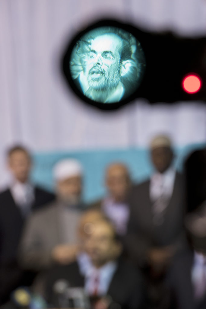 Nihad Awad, executive director and co-founder of the Council on American-Islamic Relations (CAIR), seen through the viewfinder of a television camera, speaks during the press conference. With him are Abdul Mubarak-Rowe, left, communications director of CAIR-New Jersey, and Mayor Steve Fulop. Leaders of the Muslim community together with leaders of other interdenominational religious groups and local politicians, spoke out against presidential candidate Donald Trump