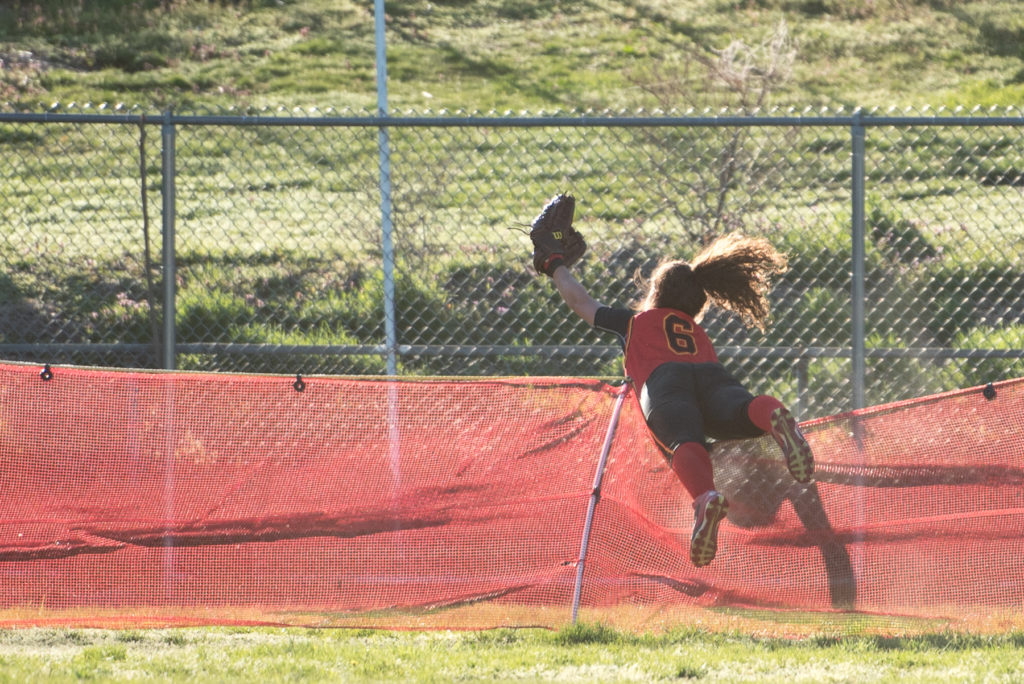 North Bergen's left fielder Cassandra Minyetty trips over a fence trying to catch a hit by Kearny's Sydney Pace, during the softball game at Gunnell Oval in Kearny on Wednesday, April 20, 2016. Reena Rose Sibayan | The Jersey Journal