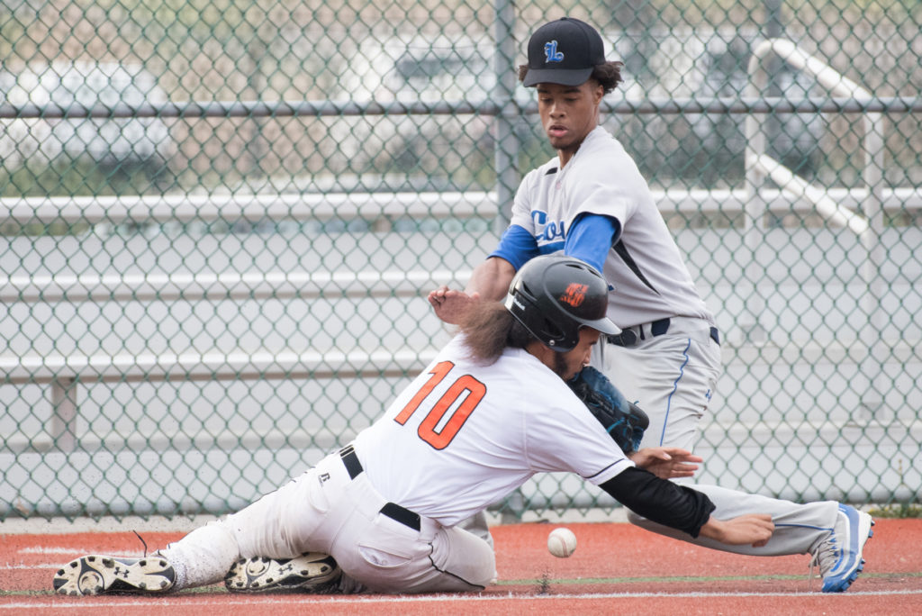 Snyder's Jorge Mejia collides with the glove of Lincoln's Shakeel Abrams at third base gets an R.B.I during the baseball game at Lincoln Park in Jersey City on Friday, April 22, 2016. Reena Rose Sibayan | The Jersey Journal