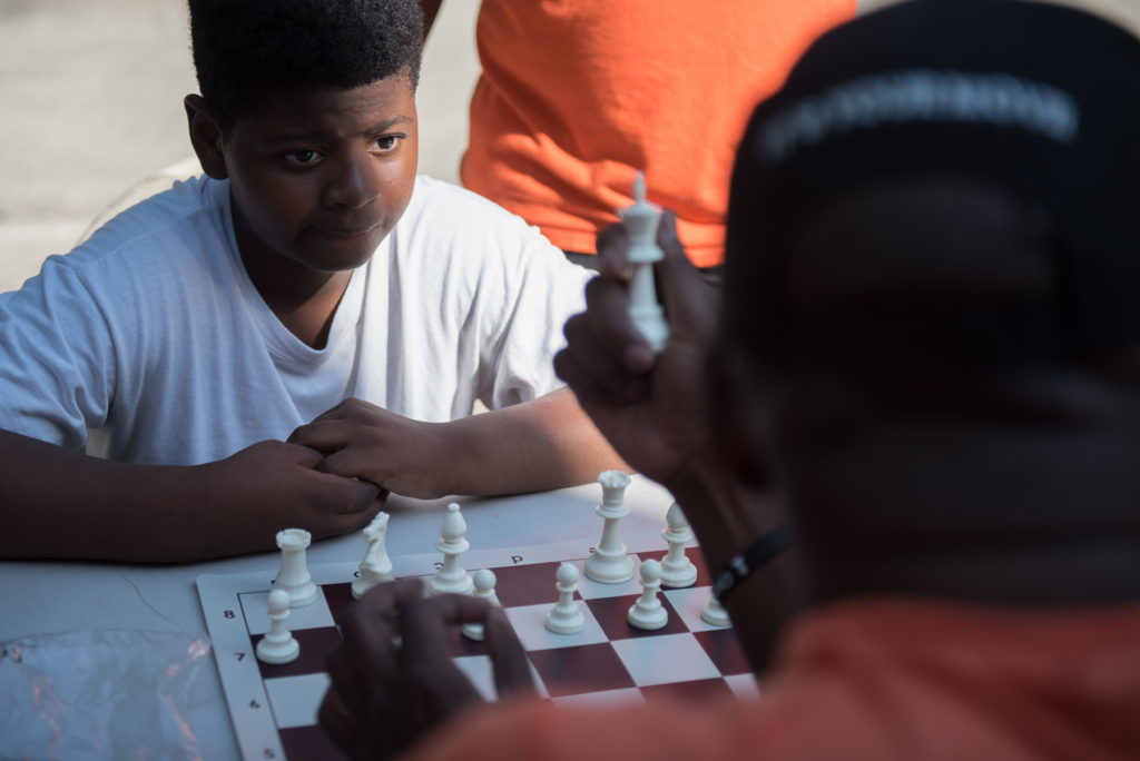 Kids like Tarren Brown, 11, learn how to play chess from Bobby Stewart, founder of Kings Knight Chess Club, during the Wear Orange for National Gun Violence Awareness Day at Arlington Park in Jersey City on Thursday, June 2, 2016. Reena Rose Sibayan | The Jersey Journal