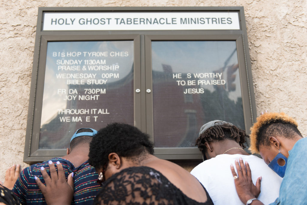 Members of the community place their hands on each other and on the church's wall as they pray during a vigil on Wednesday evening, Aug. 10, 2016, outside Holy Ghost Tabernacle Ministries on Communipaw Avenue in Jersey City where Leander Williams, 17, was fatally shot during a back-to-school party the night before. Two other shooting victims were girls ages 17 and 12. Reena Rose Sibayan | The Jersey Journal