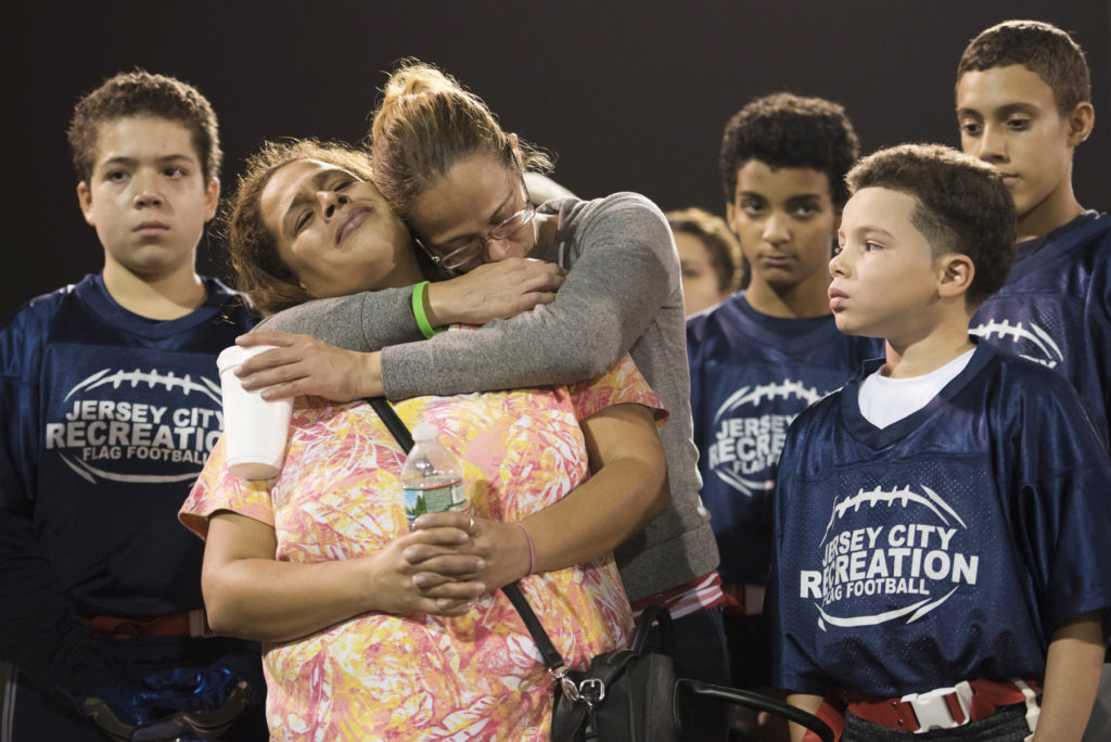 George's mother, Judy Gonzalez, is comforted by her sister, Melissa, surrounded by his flag football teammates. A memorial service is held for George Gonzalez at Enos Jones Park on Thursday, Oct. 19, 2016, where a prayer was led by Rev. Thomas Quinn of St. Michael Church and a monetary donation of $1,100 was presented to his family by Jersey City Recreation Director Kevin Williamson in behalf of the Jersey City Recreation Franco Field Flag Football League. Gonzalez, 11, was fatally struck by a jitney bus at the intersection of Kennedy Boulevard and Neptune Avenue in Jersey City on Oct. 14. Reena Rose Sibayan | The Jersey Journal