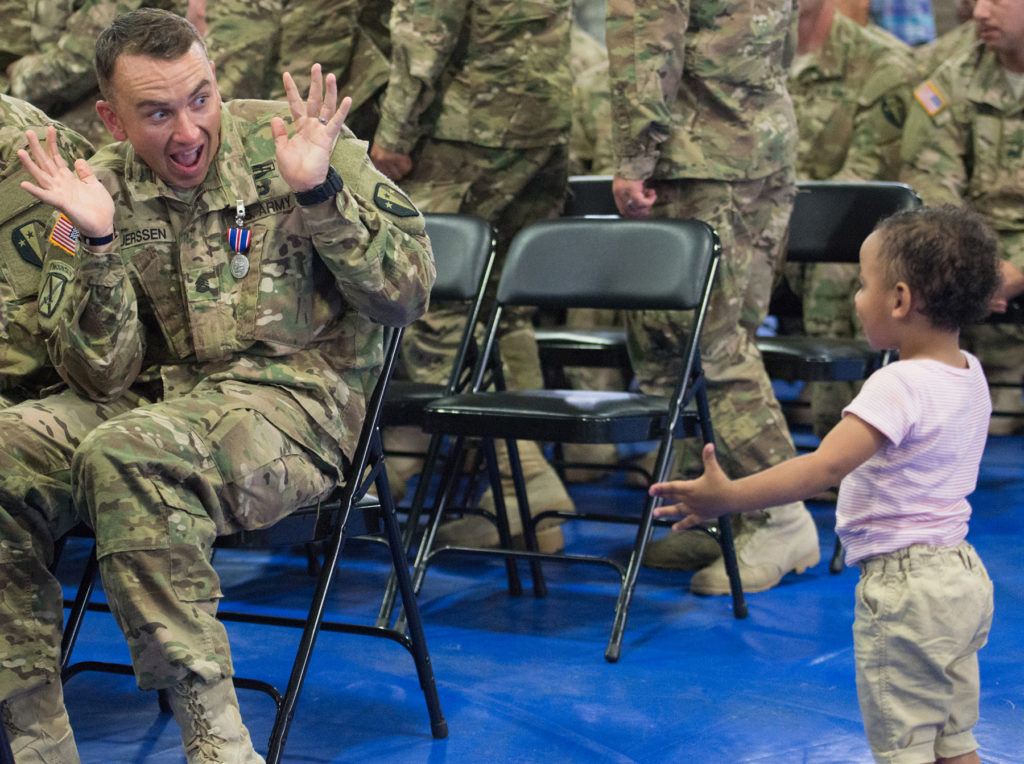 Ssgt. Guy Luerssen, 29, of Brooklyn, plays peek-a-boo with his two-year-old son, Oliver. Families and dignitaries welcome home 160 soldiers of the New Jersey Army National Guard's Alpha Company, 2-113th Infantry Battalion, after a nine-month deployment in the Persian Gulf, with a ceremony held at the Jersey City armory on Thursday, June 25, 2015. Reena Rose Sibayan | The Jersey Journal